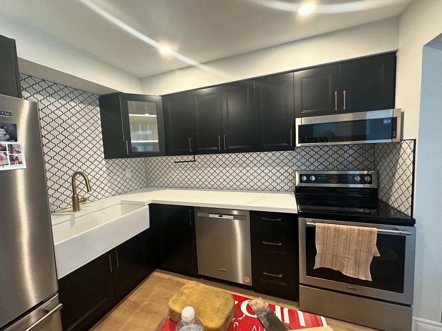 Completed kitchen with black cabinets and white countertops