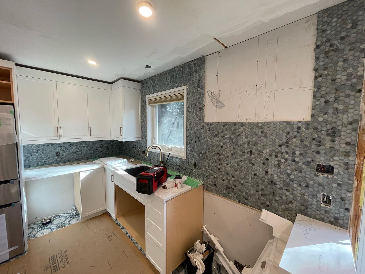 Kitchen renovation in progress with new cabinets and backsplash